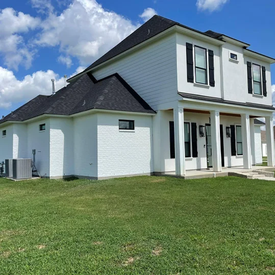 Completed exterior paint job — white two-story house with black shutters