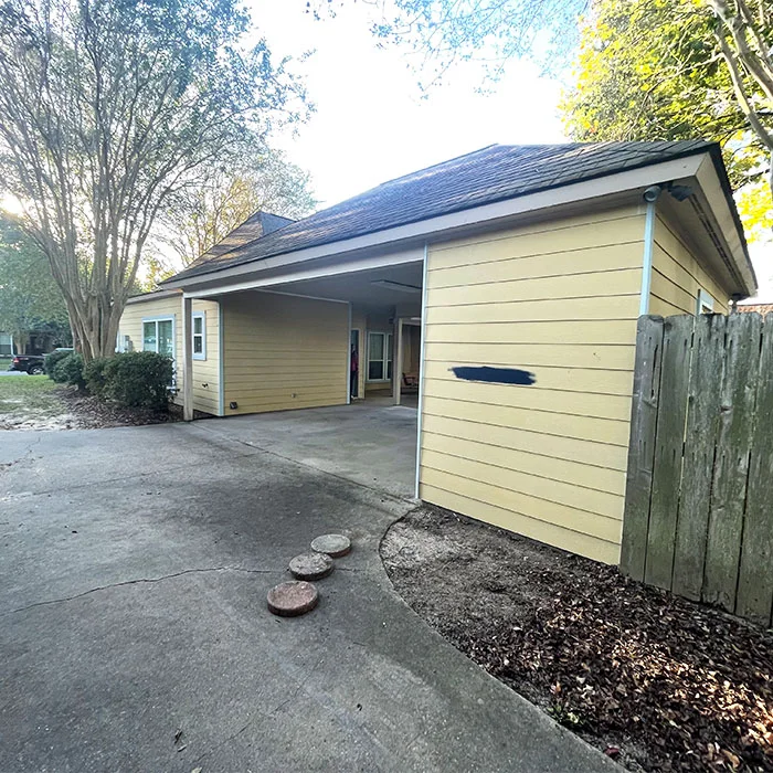 Yellow siding with a primed repair patch — exterior repair in progress